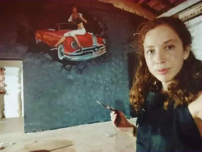 עדן לוריה לצד ציור קיר שיצרה